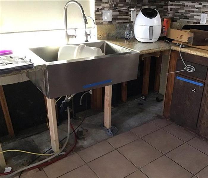The underneath of a kitchen sink stripped bare.