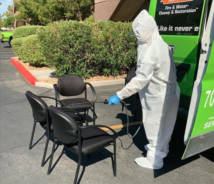person in PPE cleaning a chair.