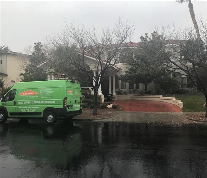Green SERVPRO van parked outside of a large one story building.