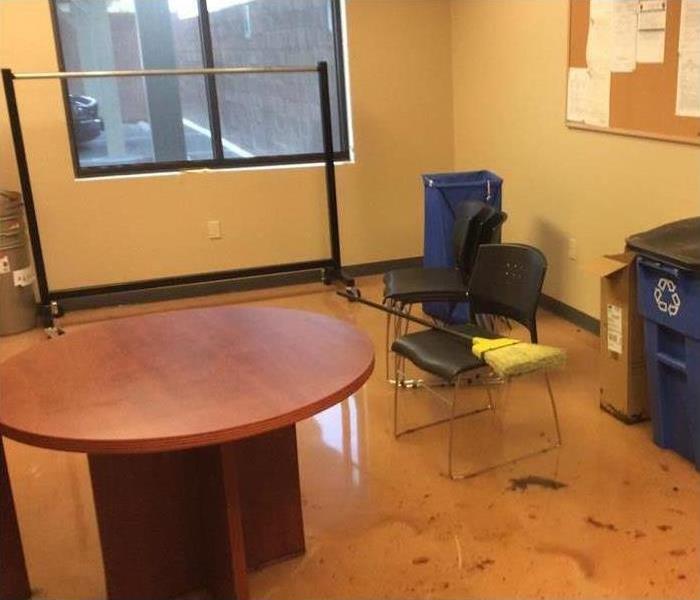 office, round table, black plastic chairs, broom on top of chairs, floodwaters inside the office